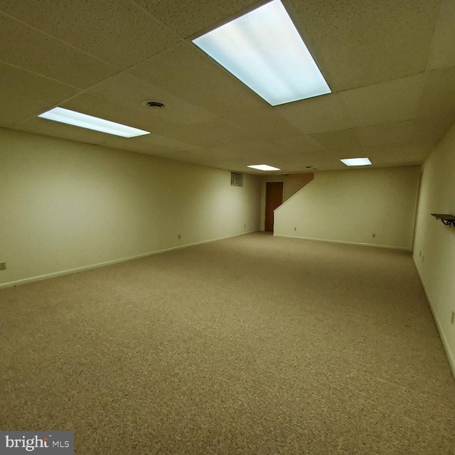 basement featuring a paneled ceiling and carpet floors