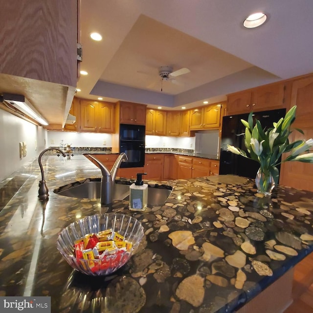 kitchen with a tray ceiling, kitchen peninsula, ceiling fan, and black appliances