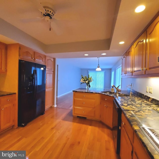 kitchen featuring black appliances, sink, decorative light fixtures, light hardwood / wood-style floors, and kitchen peninsula