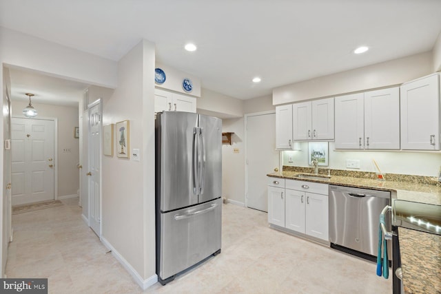 kitchen with light stone countertops, sink, white cabinets, and stainless steel appliances