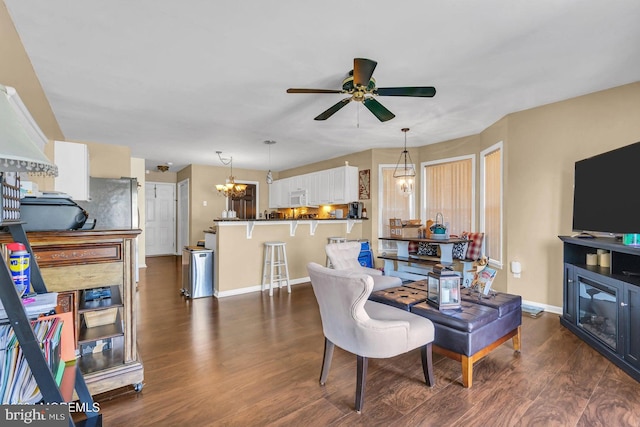 living room featuring ceiling fan with notable chandelier and dark hardwood / wood-style flooring