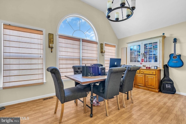 dining area with vaulted ceiling, light hardwood / wood-style flooring, and an inviting chandelier