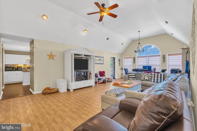 living room with ceiling fan with notable chandelier, lofted ceiling, and light hardwood / wood-style flooring