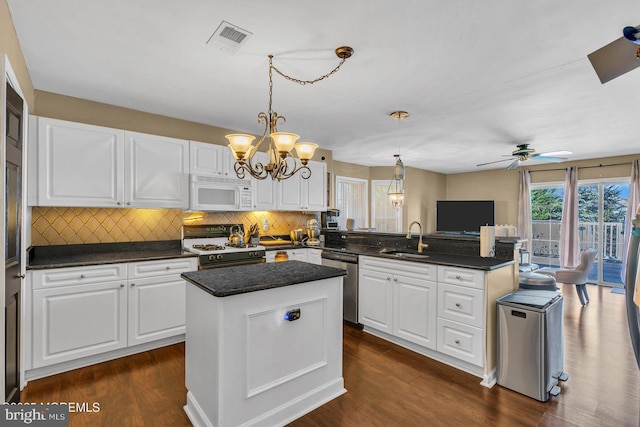 kitchen featuring white cabinets, white appliances, a kitchen island, and sink