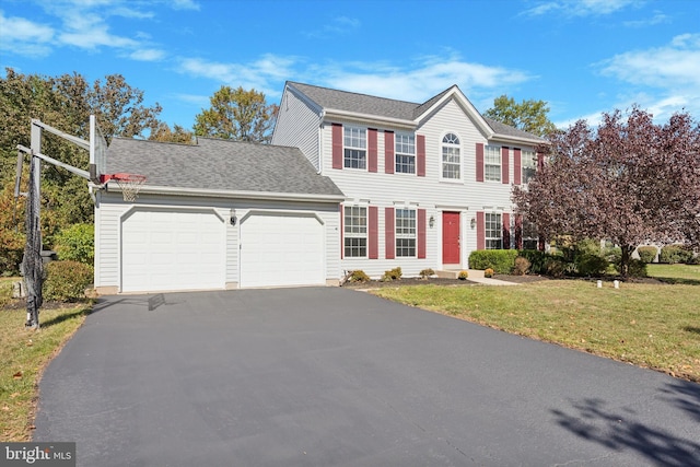 colonial inspired home featuring a garage and a front lawn