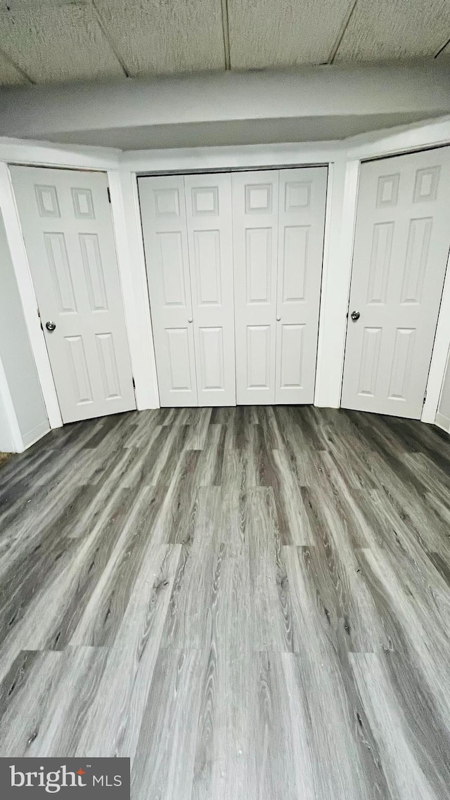 unfurnished bedroom featuring hardwood / wood-style floors and two closets