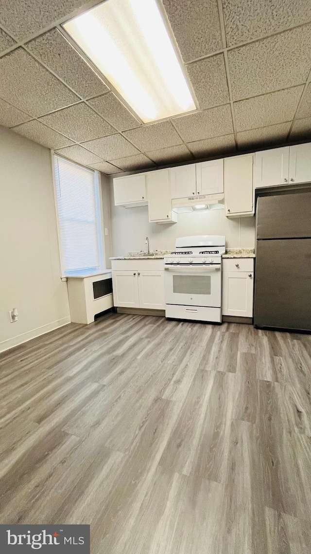 kitchen featuring a paneled ceiling, light wood-type flooring, stainless steel refrigerator, white cabinetry, and white range with gas cooktop