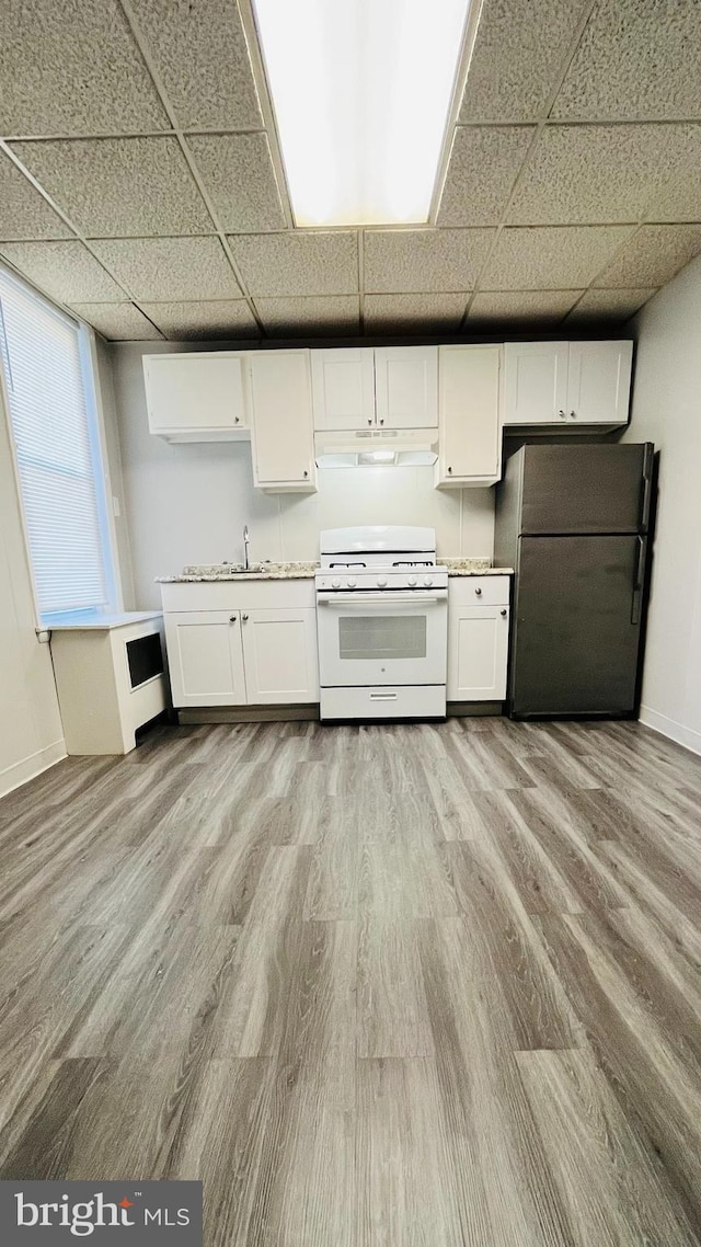 kitchen featuring white cabinetry, a drop ceiling, white range with gas stovetop, refrigerator, and light hardwood / wood-style floors