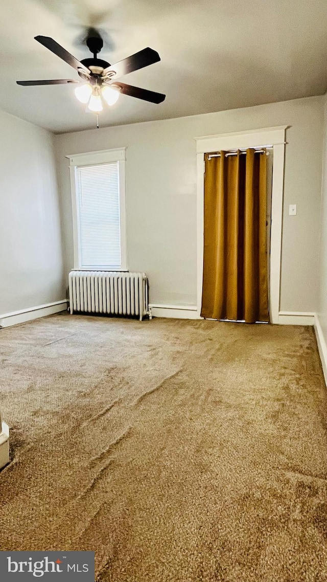 unfurnished room with carpet, ceiling fan, and radiator heating unit