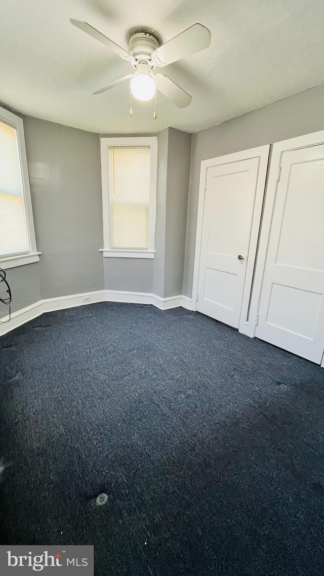 unfurnished room featuring dark colored carpet and ceiling fan