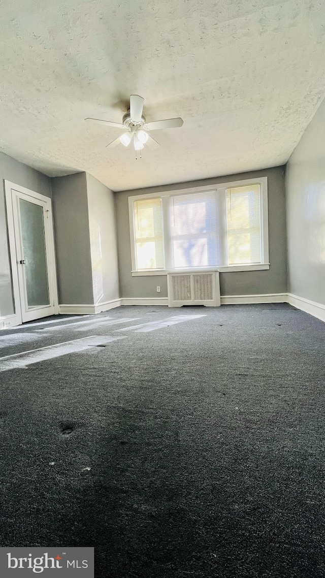 unfurnished room with radiator, ceiling fan, carpet floors, and a textured ceiling