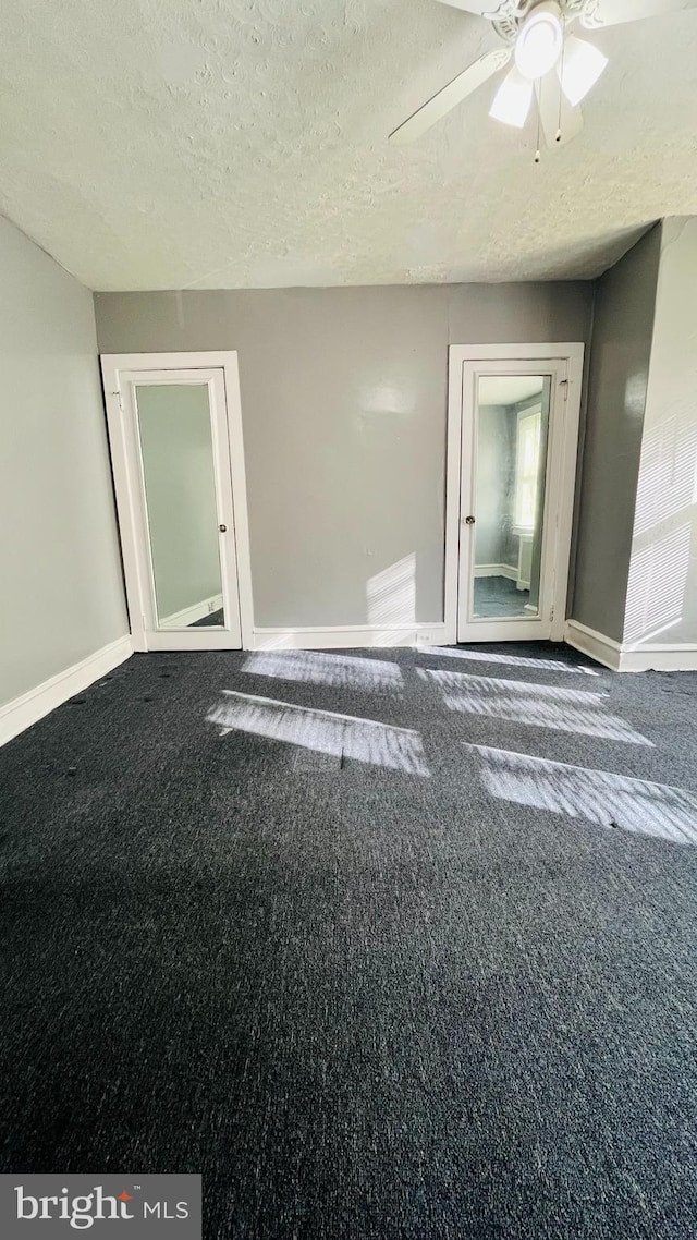 carpeted spare room featuring ceiling fan and a textured ceiling