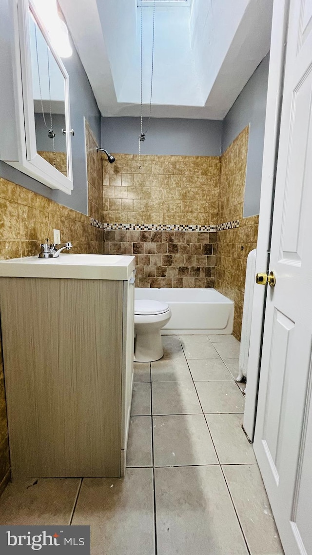 full bathroom with shower / bath combination, tile patterned floors, vanity, tile walls, and toilet