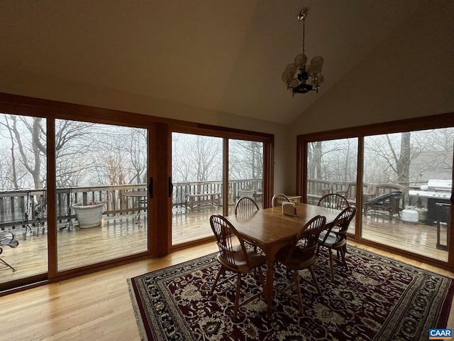 sunroom with plenty of natural light, vaulted ceiling, and an inviting chandelier