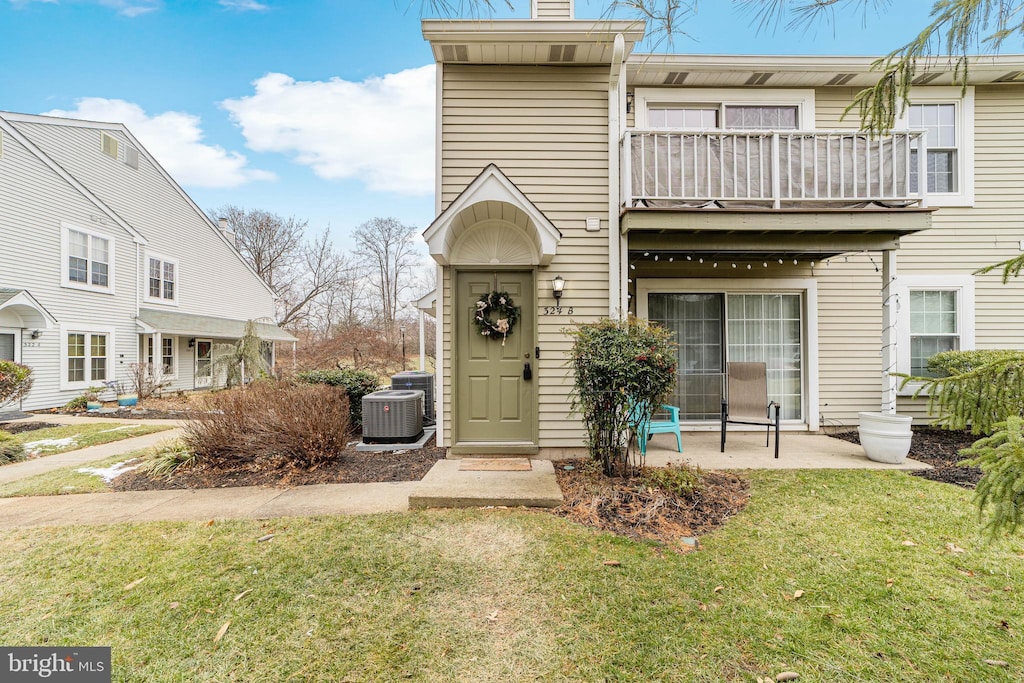 view of property featuring cooling unit, a balcony, a patio, and a front yard