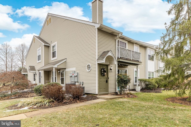 view of front of house featuring a balcony and a front lawn