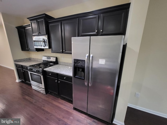 kitchen with light stone counters, dark hardwood / wood-style flooring, and stainless steel appliances