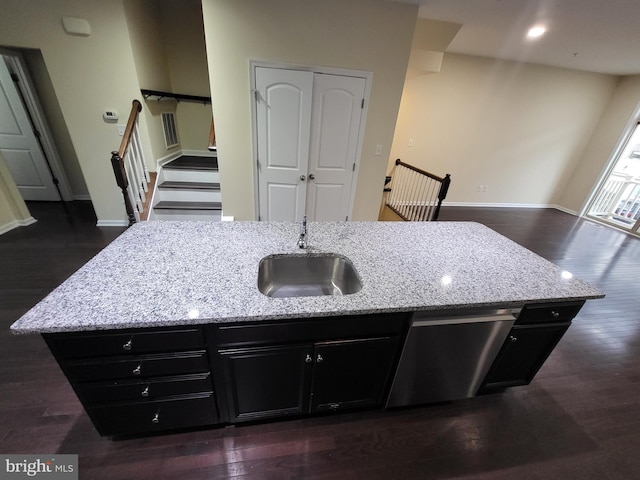 kitchen featuring light stone countertops, dark hardwood / wood-style flooring, a kitchen island with sink, sink, and dishwasher