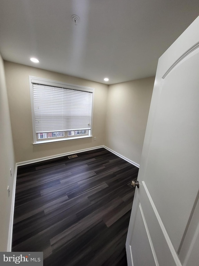 unfurnished room with dark wood-type flooring