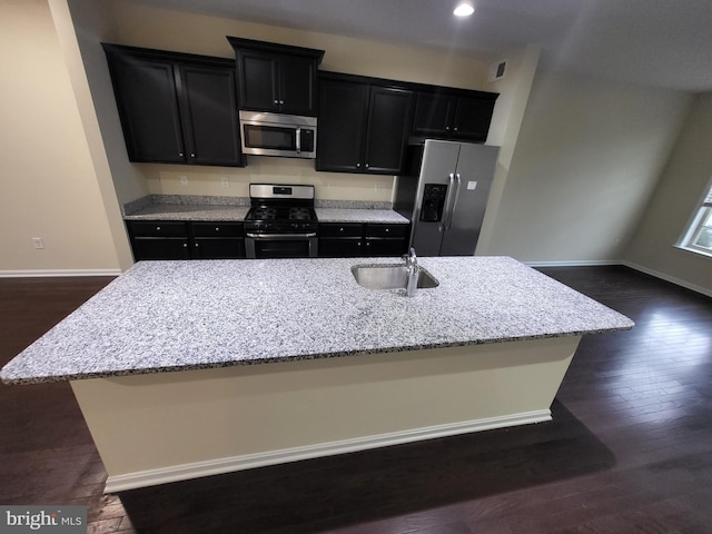 kitchen with dark wood-type flooring, sink, an island with sink, and stainless steel appliances