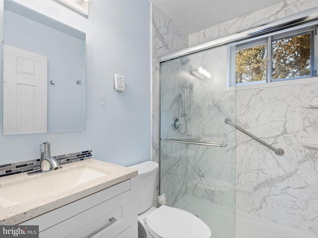 bathroom with an enclosed shower, vanity, toilet, and backsplash