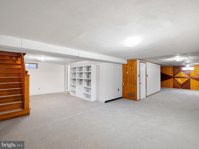 basement featuring light colored carpet and wooden walls