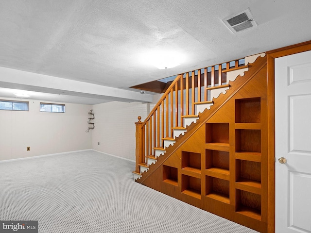 basement with carpet, built in shelves, and a textured ceiling