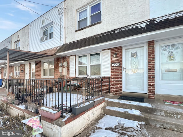 snow covered property entrance with a porch