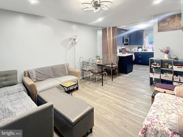 living room with light hardwood / wood-style floors and ceiling fan