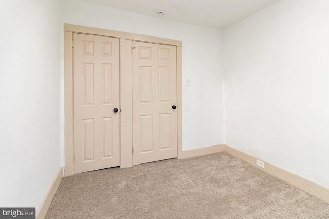 unfurnished bedroom with light colored carpet and a closet