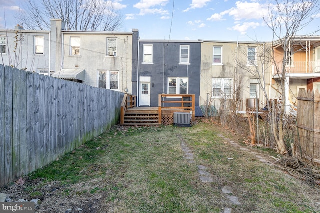 back of property with a deck and central AC