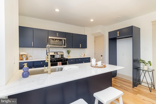 kitchen featuring kitchen peninsula, appliances with stainless steel finishes, tasteful backsplash, and light hardwood / wood-style floors