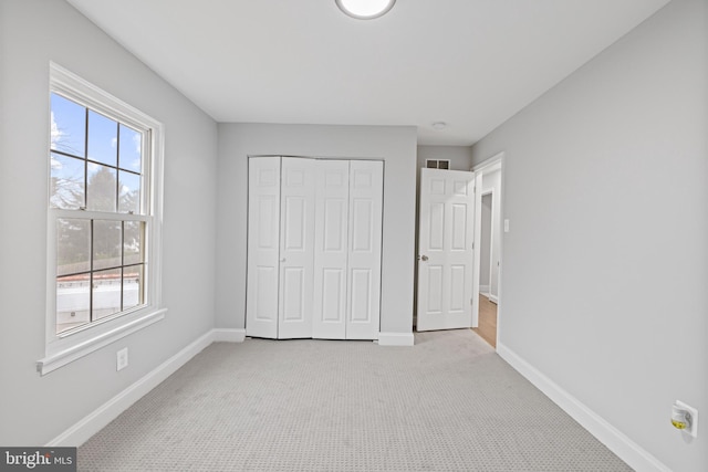 unfurnished bedroom featuring multiple windows, light colored carpet, and a closet