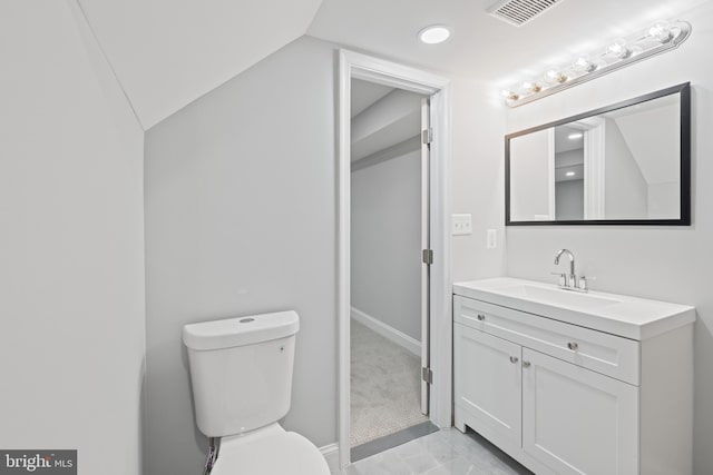 bathroom with vanity, toilet, and lofted ceiling