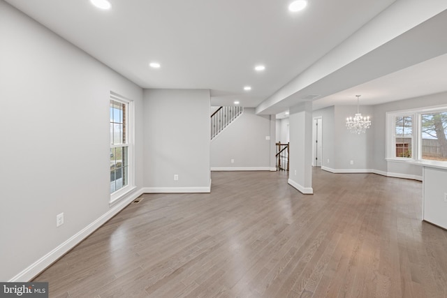 unfurnished living room with a chandelier and hardwood / wood-style flooring