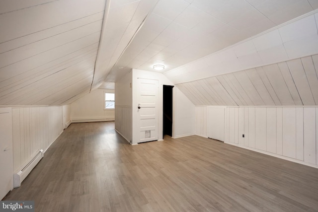 additional living space with lofted ceiling, wood walls, baseboard heating, and wood finished floors