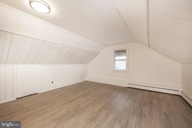 bonus room with a baseboard heating unit, lofted ceiling, and wood finished floors