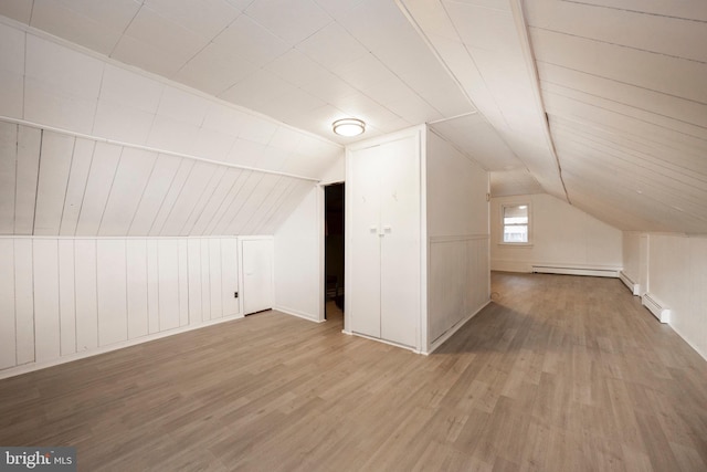 bonus room with vaulted ceiling, a baseboard heating unit, and light wood-style floors