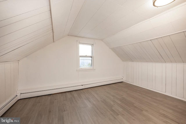 bonus room with a baseboard heating unit, lofted ceiling, and wood finished floors