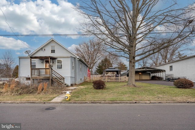 view of front facade with aphalt driveway, fence, a gazebo, a detached carport, and a front yard