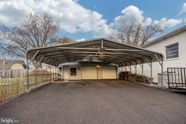 view of parking / parking lot with a garage and fence