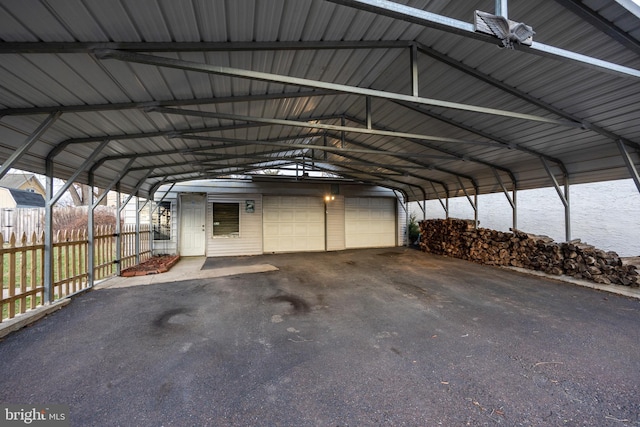 view of car parking featuring a garage, a carport, and fence