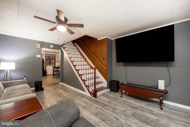 living room with wood-type flooring, ceiling fan, and ornamental molding