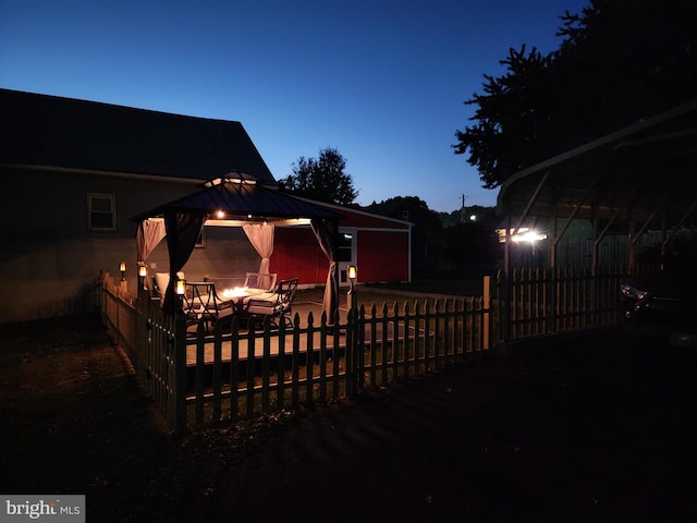 back of property at dusk with fence and a gazebo