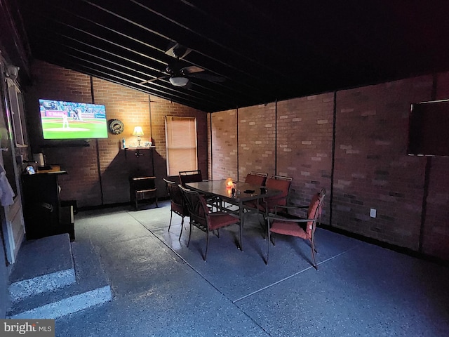 dining area with vaulted ceiling and brick wall