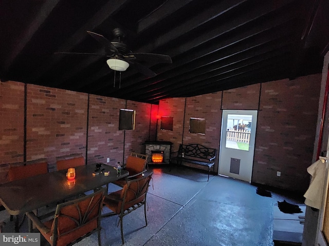 interior space featuring lofted ceiling, a wood stove, brick wall, and a ceiling fan