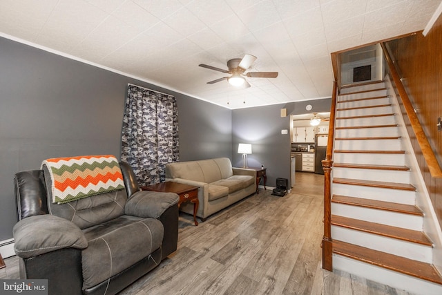 living room featuring stairs, ornamental molding, wood finished floors, and a ceiling fan