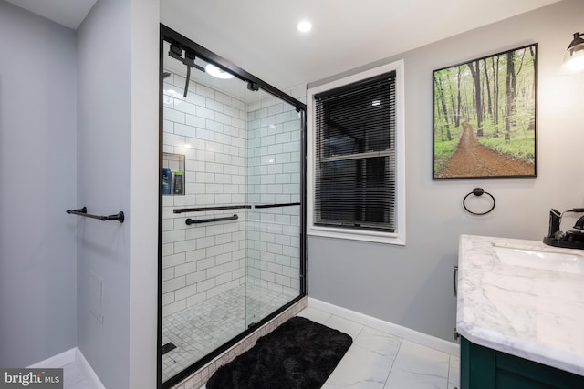 full bath with baseboards, vanity, marble finish floor, and a shower stall