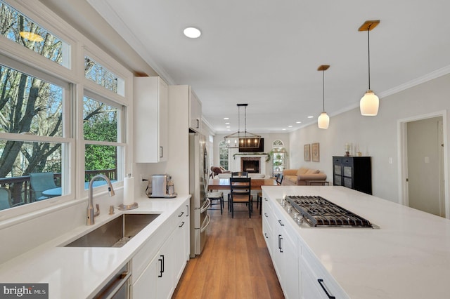 kitchen with stainless steel appliances, hanging light fixtures, sink, and white cabinets