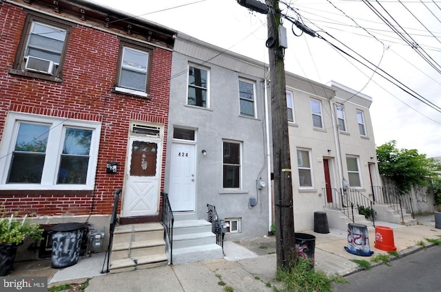 townhome / multi-family property with entry steps, brick siding, and stucco siding